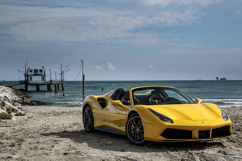 yellow Ferrari 458 Italia car on seashore near dock under white clouds HD wallpaper