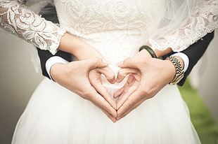 couple in wedding attire both hands in heart forms
