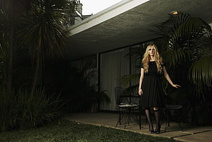 woman wearing black dress standing outside house