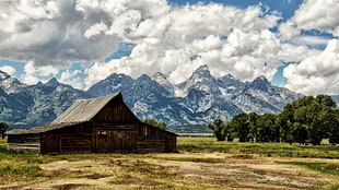 brown barn with background of mountain and cloudy sky
