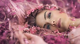 closeup photo of woman wearing pink flower headdress lying on ground