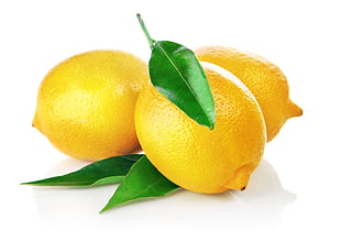 three yellow lemon with leaves on white surface
