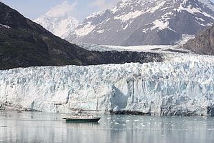 cruiser boat sailing near wall of ice