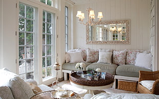 round brown wooden table, white and gray couch with throw pillows with white wooden frame glass window