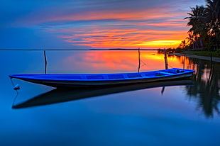 blue wooden boat on top of body of water