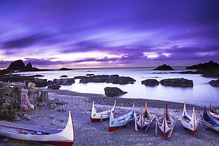 seven boats on seashore under purple clouds blue sky, ponso