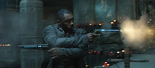man in gray jacket holding two guns