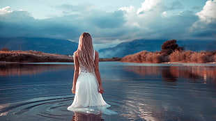 woman in white sleeveless dress on body of water