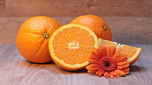 sliced orange fruit against two orange fruits HD wallpaper