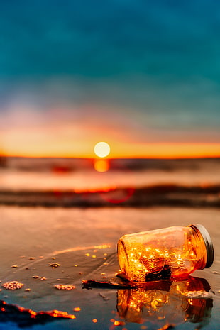 selective photo of mason jar with light during sunset