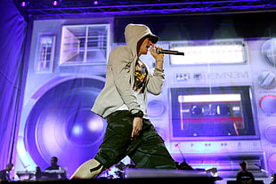 Eminem wearing gray zip-up hoodie and holding cordless microphone
