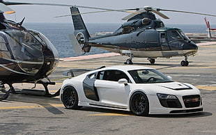 white Audi R8 1st gen coupe near two black helicopters