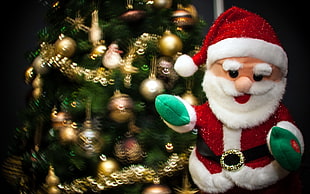 Santa Claus plush toy beside green christmas tree