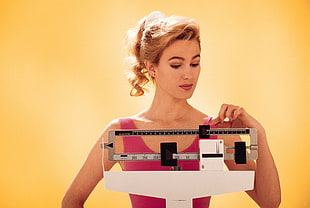 woman in pink using manual weighing scale