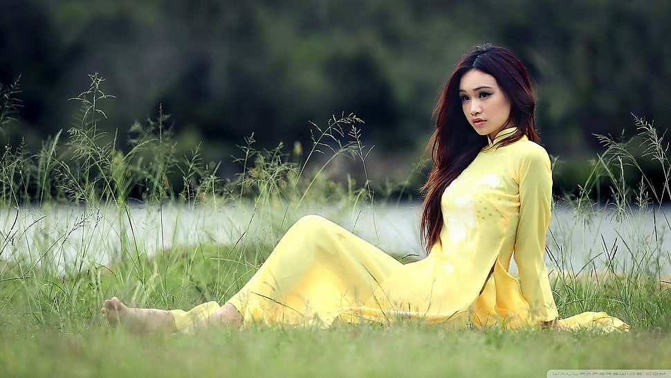 woman in yellow long-sleeved dress laying on grass during daytime HD wallpaper