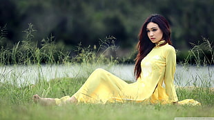 woman in yellow long-sleeved dress laying on grass during daytime