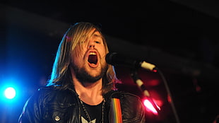 blond man with long hair singing in front of mic