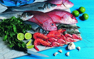 assorted seafood on blue table with sliced lime and garlic