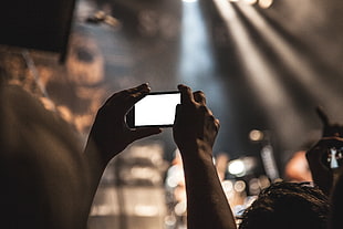 depth of field photography of person holding up smartphone with white screen display