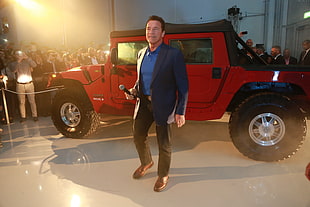 man holding microphone beside red sport utility vehicle