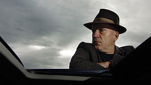 man in black and brown fedora hat under heavy clouds