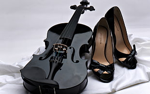 photo of black violin with pair of black peep-toe heels on white textile