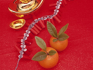 two orange fruits on top of red surface