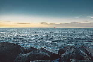 body of water beside of rocks HD wallpaper
