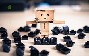 selective focus photography of box formed man surrounded with keyboard keys
