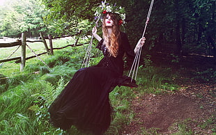woman wearing black gown while riding swing chair