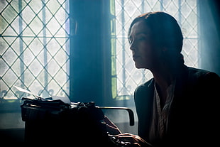 woman sitting near type writer inside dark room