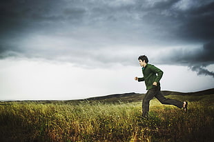 man in green long sleeve shirt passing through green grass field