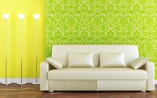 white fabric couch with throw pillows beside 3 silver torchieres