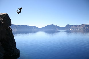 person jump off in a cliff photography