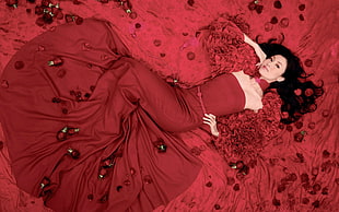 woman in red strapless dress lying on roses