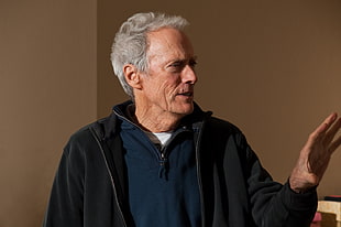man wearing blue hoodie standing beside wall