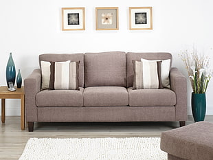 gray suede couch between brown wooden side table and blue ceramic vase
