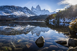 silent body of water beside trees under cloudy blue sky, fitz roy, argentina