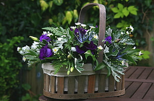 purple and green flower bouquet on wooden basket