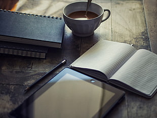 white book beside tablet computer on table