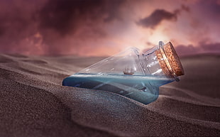 clear glass cork bottle on gray sand
