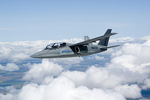 flying grey and blue N52ITA fighter jet above clouds during daytime