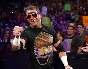 male wrestler wearing black and brown crew-neck t-shirt and orange framed sunglasses