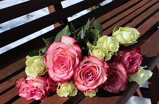 photo of bouquet of pink and white roses on brown wooden bench