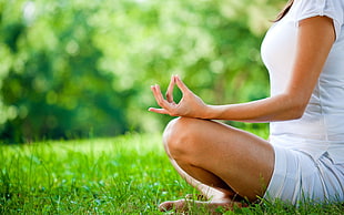 selective focus photography of woman meditating on grass