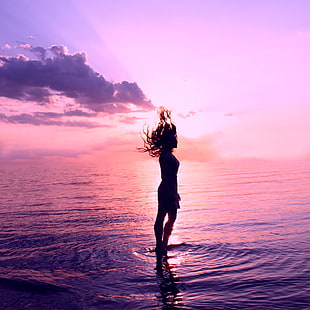 silhouette photo of a woman standing on a body of water