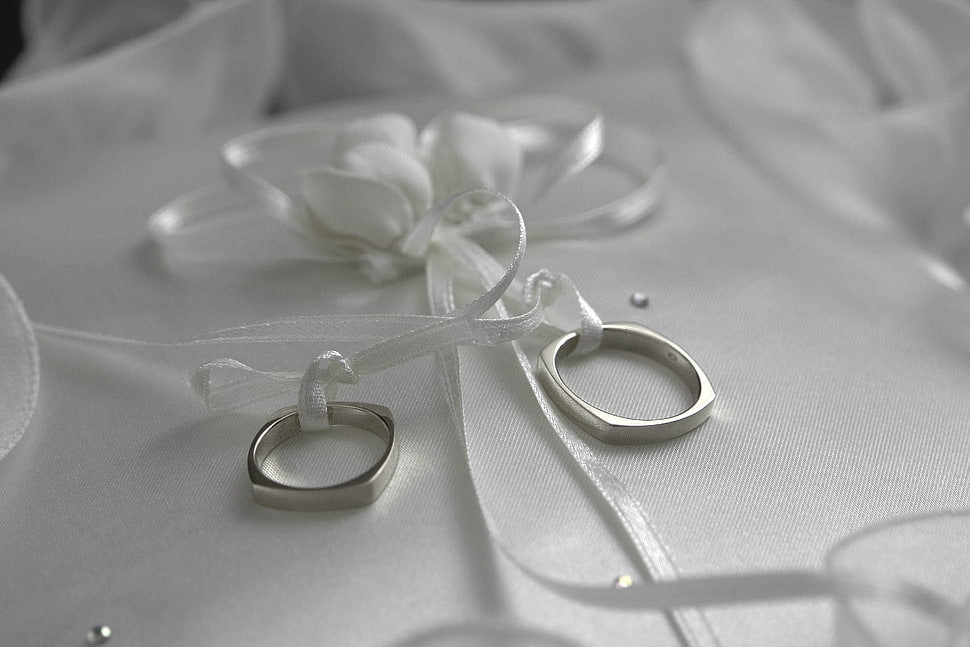 two silver band rings on white ribbon HD wallpaper