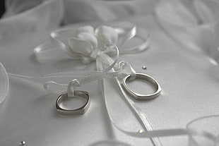 two silver band rings on white ribbon