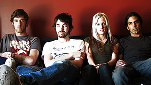 three men and one women sitting on black sofa