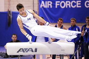 gymnast on balance beam while the four men watching at the back
